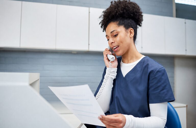 A practice receptionist taking a patient call at her desk
